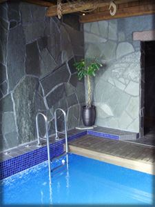 Indoor pool with walls of gray natural stone.