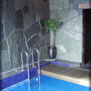 Indoor pool with walls of gray natural stone.