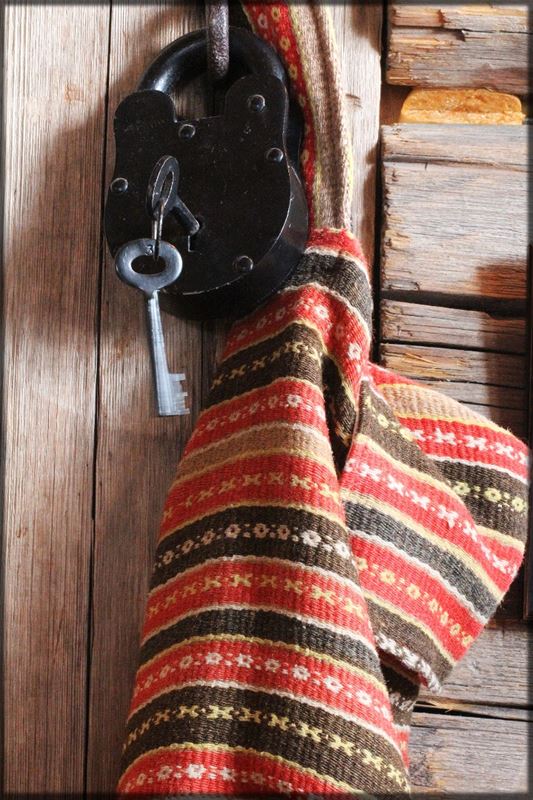 An old key in an old locker with a woven towel beside the door. 