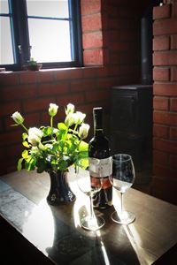 Detalj på två vinglas, en vinflaska, en bukett vita tulpaner i en blå Nittsjö-vas.