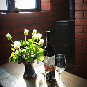Detalj på två vinglas, en vinflaska, en bukett vita tulpaner i en blå Nittsjö-vas.