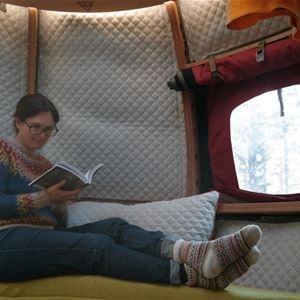 Tjej som ligger i trädkoja och läser bok.