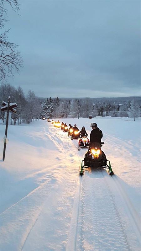 Snowmobiles in a row driving in darkness