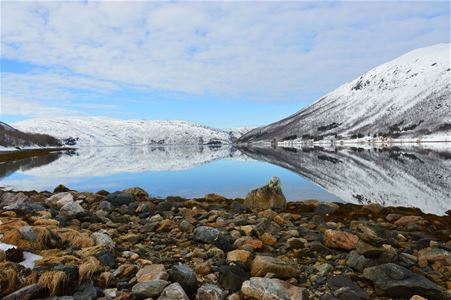 Fjære med klart hav og fjell i bakgrunnen