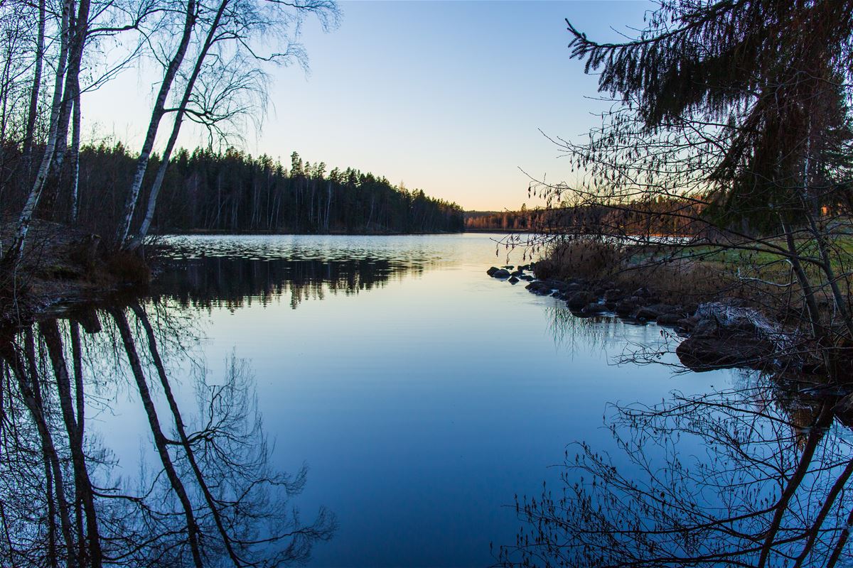 Blank sjö i solnedgång.