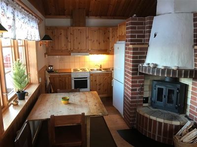 Kitchen with cupboards of pine, dining table and a fireplace.