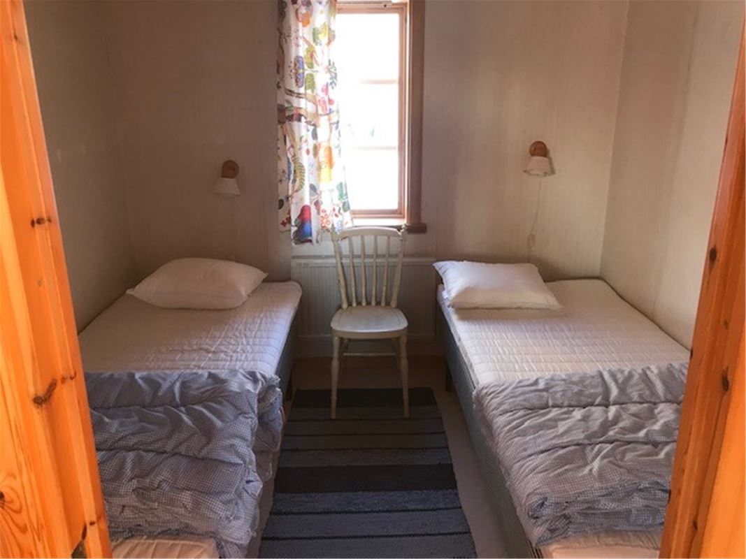Two single beds placed on each side of a window. 