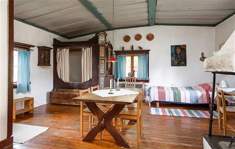 Large room with wooden floor, single bed, dining table, traditional cupboard bed.