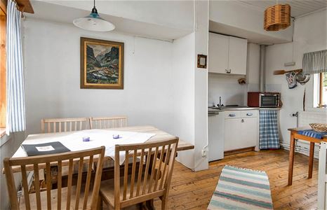 Wooden dining furniture in a white room close to the pentry.
