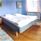 Double bed in a large room with blue walls and a wooden floor.