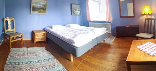 Double bed in a large room with blue walls and a wooden floor. 
