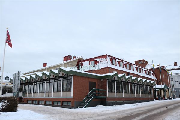 Exteriörbild med tegelklädda väggar och vitt med snö på taken. 