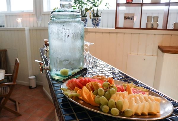 Fruktfat och en karaff med vatten på en bänk. 