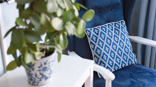 Blue upholstered chair and a flower on the table