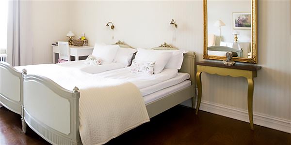 Double bed in a grey bedframe and a golden mirror with an antique table below.