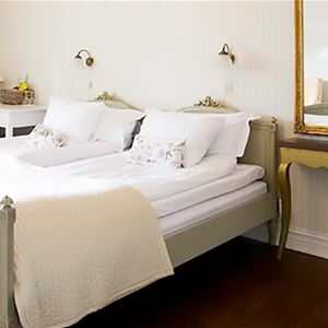 Double bed in a grey bedframe and a golden mirror with an antique table below.