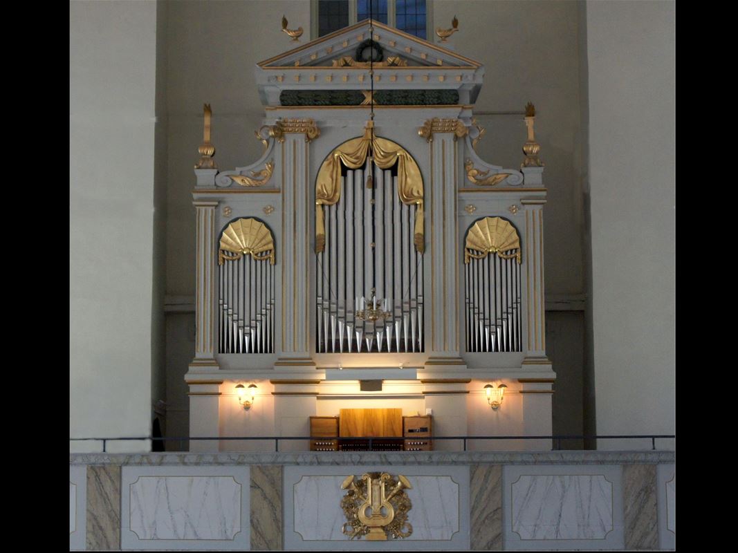 Interiörbild från kyrkan, orgel och altarfasad med gulddetaljer.