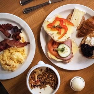 Frukost med ägg, bacon, smörgåsar och fil med müsli.
