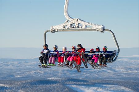 Eight persons in a lift on their way up to the top of the mountain.