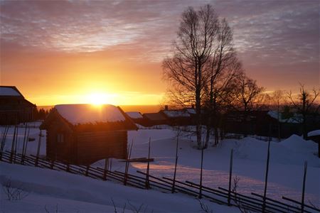 Sunset on a winter evening with a shelter and typical dalecarlian fence. 