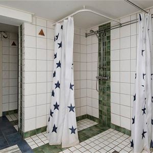 Två duschar med kaklade väggar och golv. 