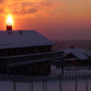 Timmerhus i solnedgång en vinterdag.