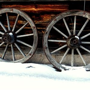 Detaljbild på två hjul i trä mot en timmervägg. 