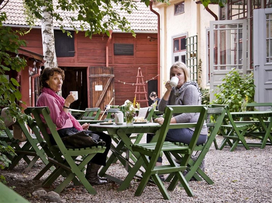 Bild från innergården, två gäster sitter vid ett bord och fikar.