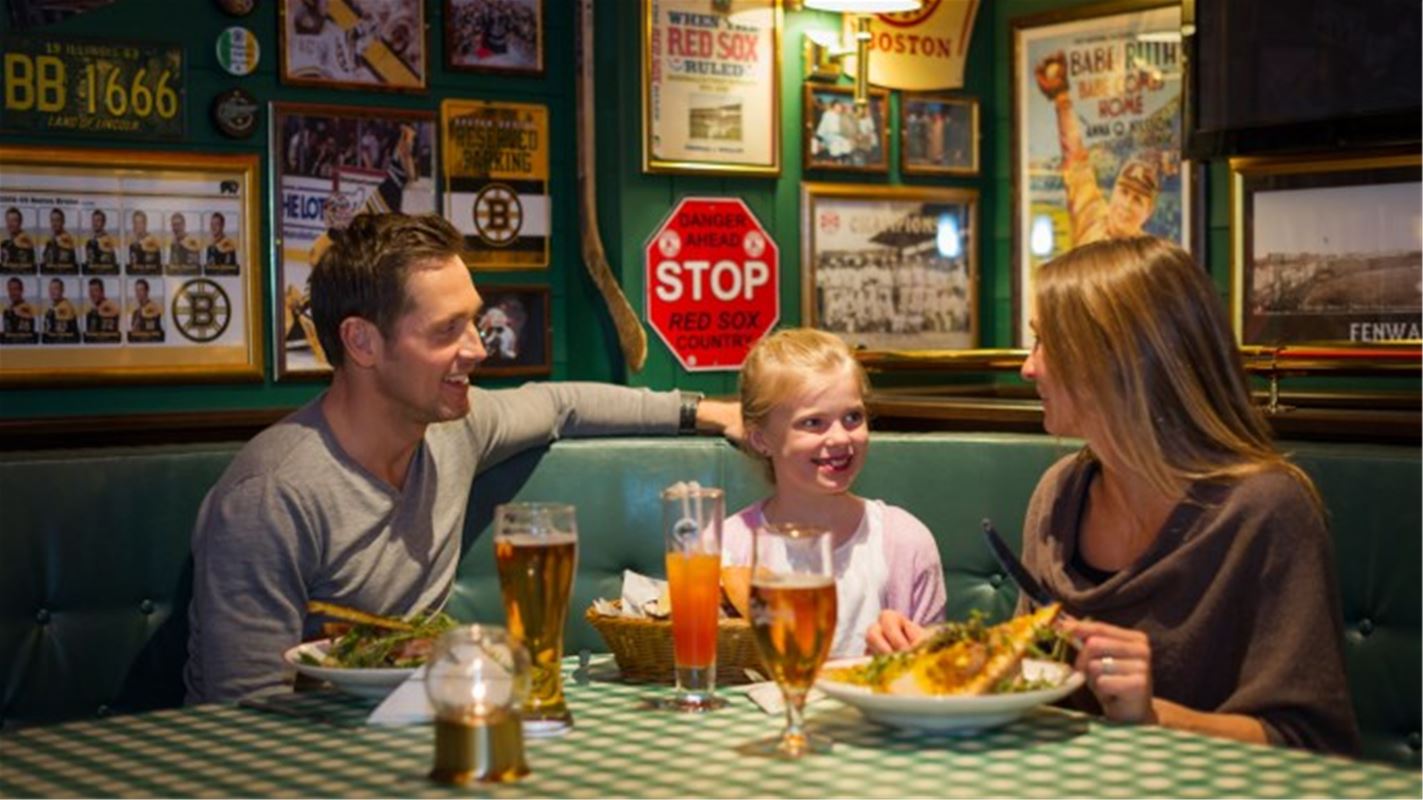 En familj, mamma, pappa och barn sitter vid ett bord med mat framför sig. 