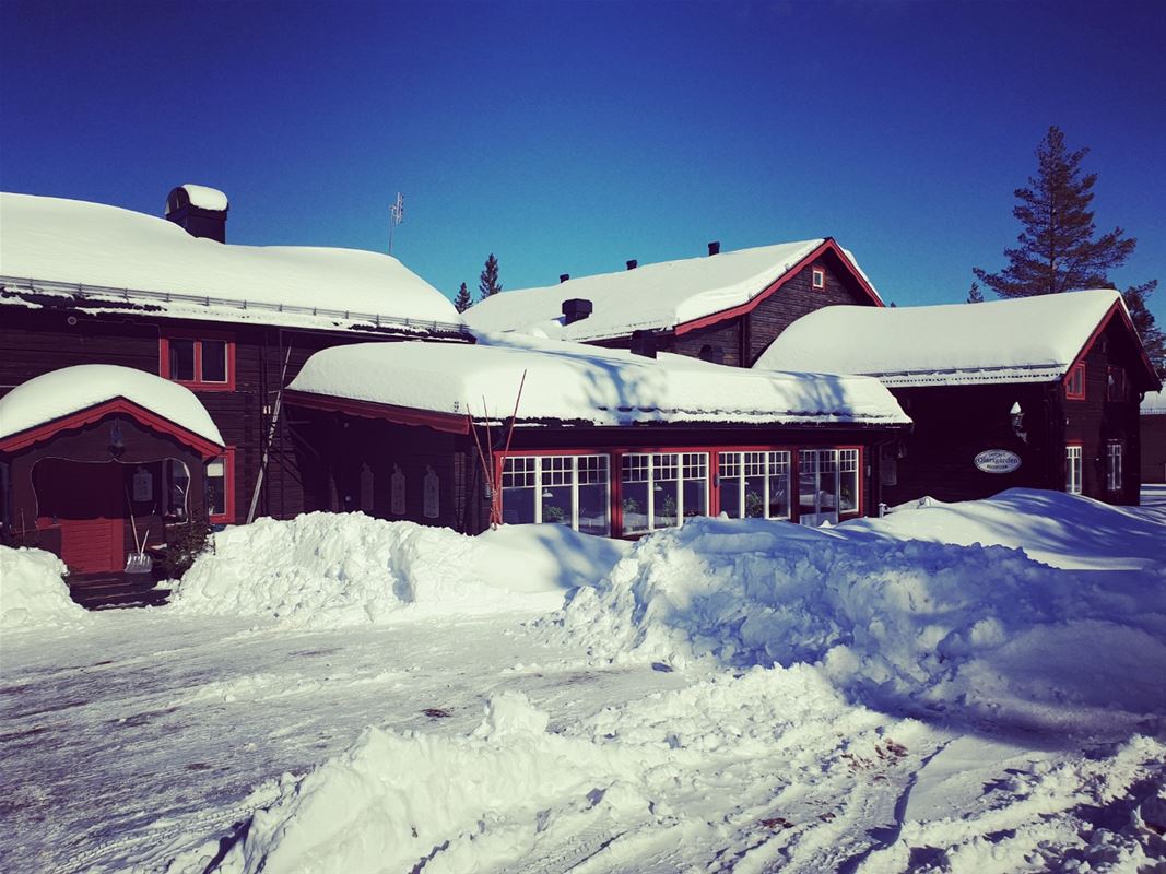 Mörkbruna timmerhus omgivna av snö.