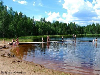 Bathing people by small lake with bathing jetty.