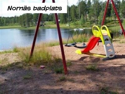 Playground with swing set in front of swimming lake.