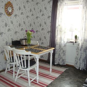 Dining table with three chairs in a room with grey patterned wallpaper. 