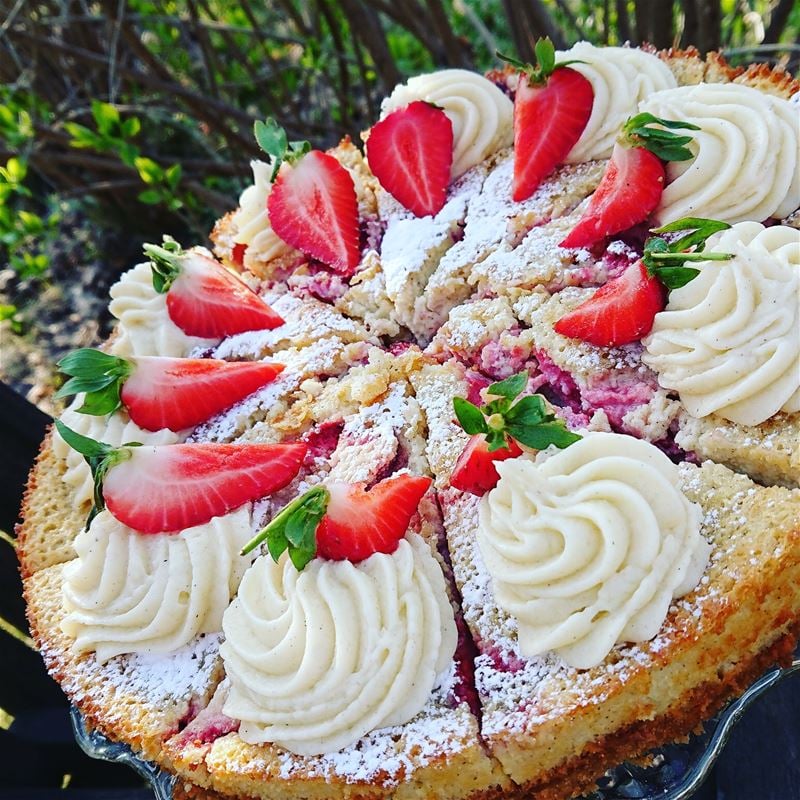 A cake divided into several pieces, sprinkled cream and a piece of strawberry on top.