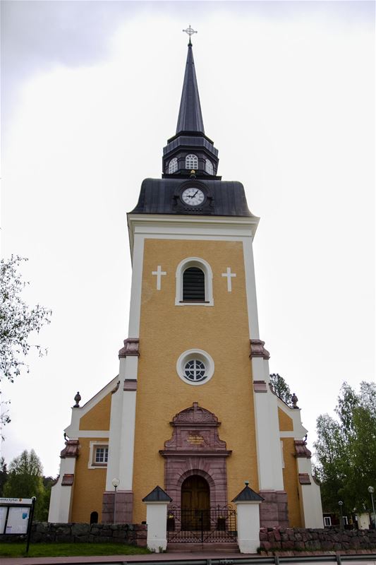 The entrance to the church which is in yellow and white with black roof.
