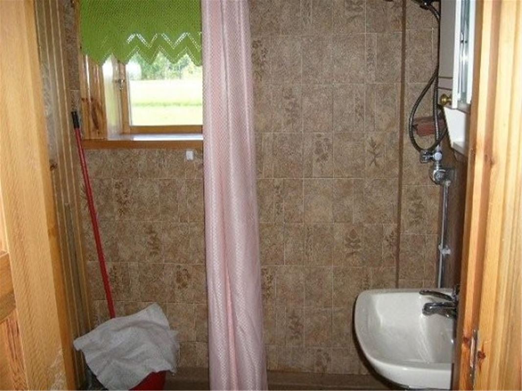 Shower with beige walls and a pink curtain.