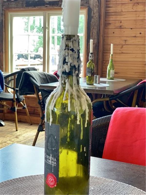 En tom vinflaska som har ett stearinljus på flaskans hals. 