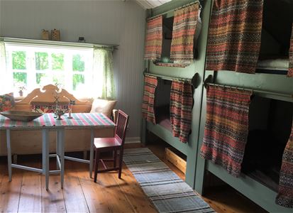 Two site-built bunkbeds with woven curtains beside the kitchen sofa and folding table.
