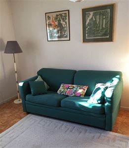 Grön soffa med golvlampa bredvid.