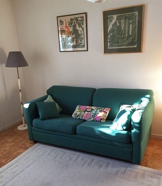 Grön soffa med golvlampa bredvid. 