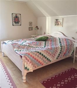 Double bed in a white frame with a patchwork quilt.