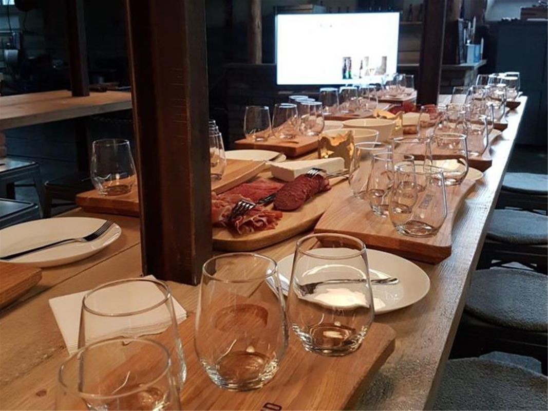 Long table with glass for beer tasting and plates where you can add different cheeses sausages and snacks.