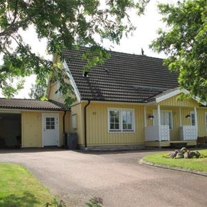 Yellow two-storey house with black tiled roof and a garage. 