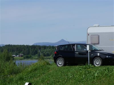 A car parked at the campsite with the mountains behind it.