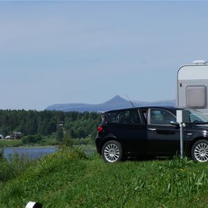 A car parked at the campsite with the mountains behind it.