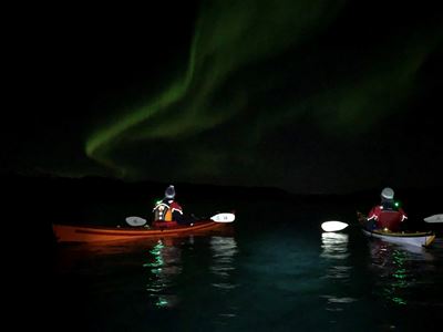 To personer i kajakk under nordlyset