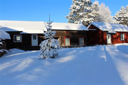Cabins in a row with snow on the roof and the ground.