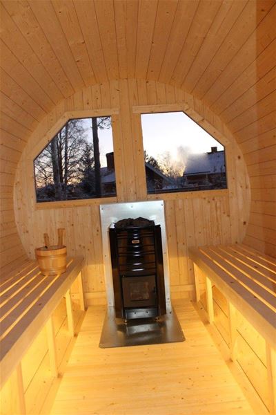 Sauna with a black stove in front of two large windows.  