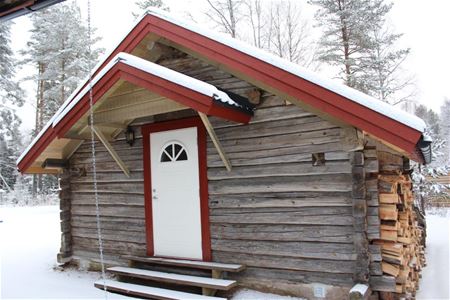 Grey log cabin with white door and snow on the doorstep. 