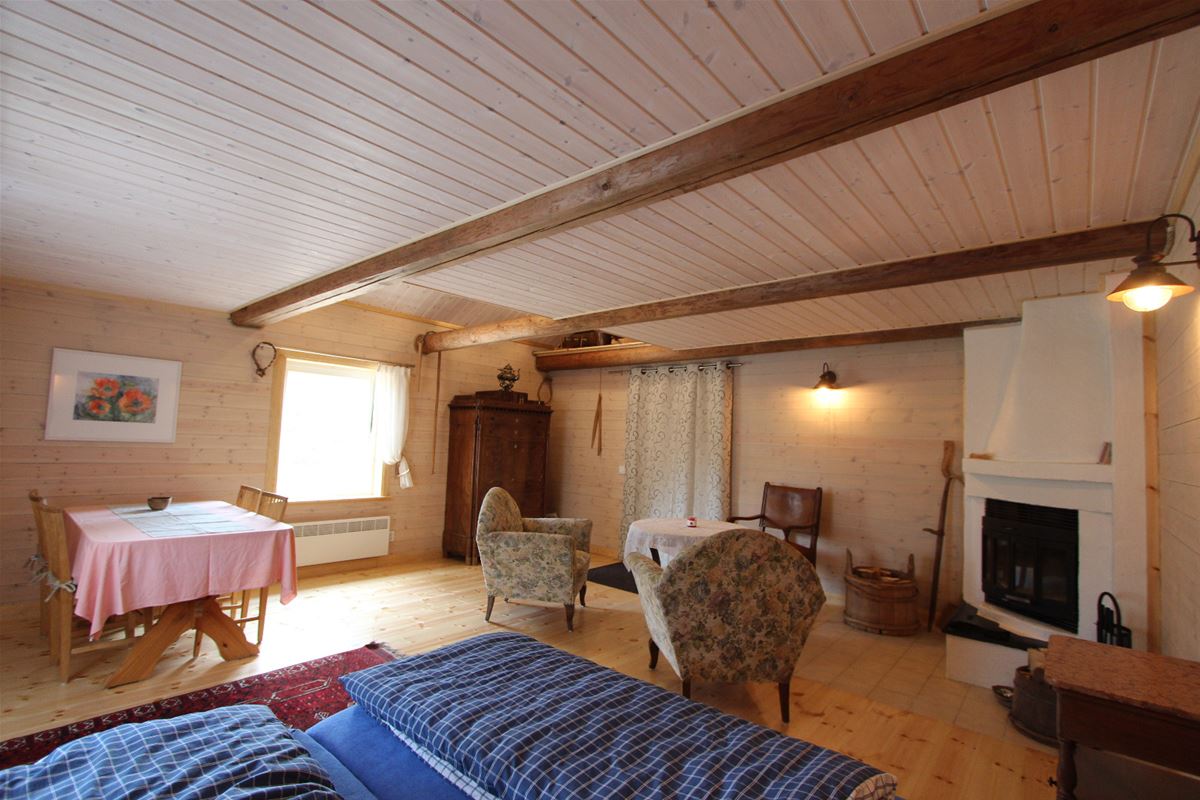 Large room with double bed,  open fire place, armchairs and a dining table. 
